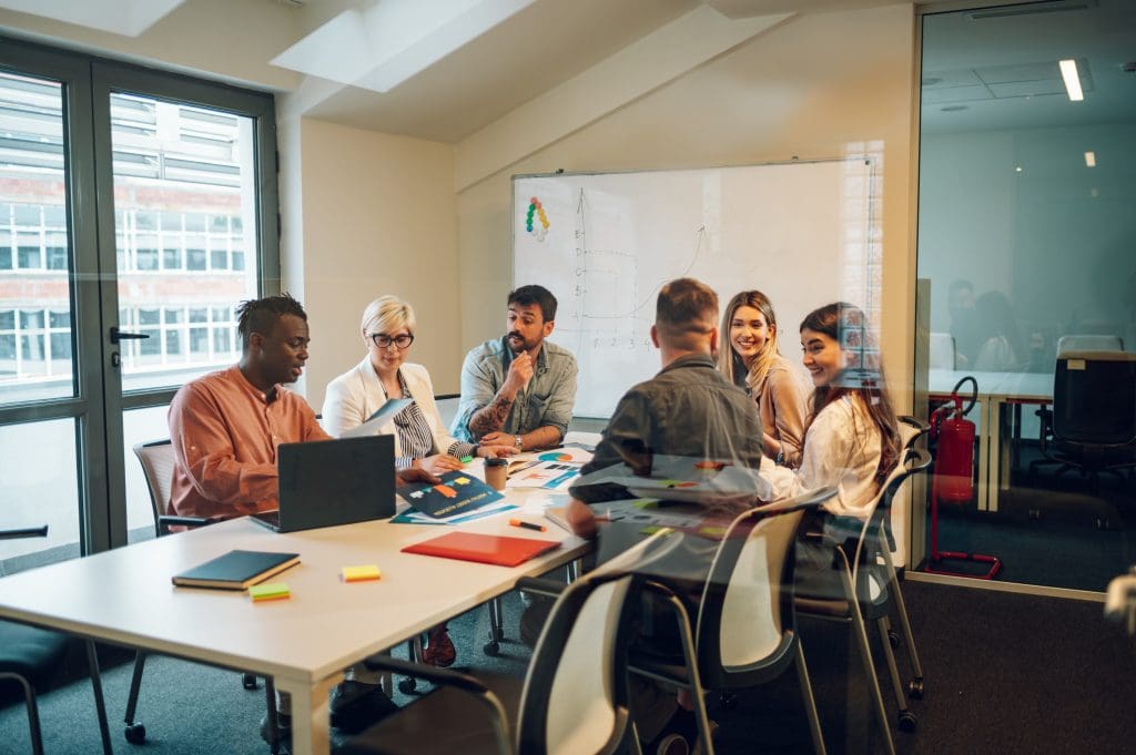 Business team on a meeting in a modern bright industrial design office interior. Team leader present project to its diverse colleagues.